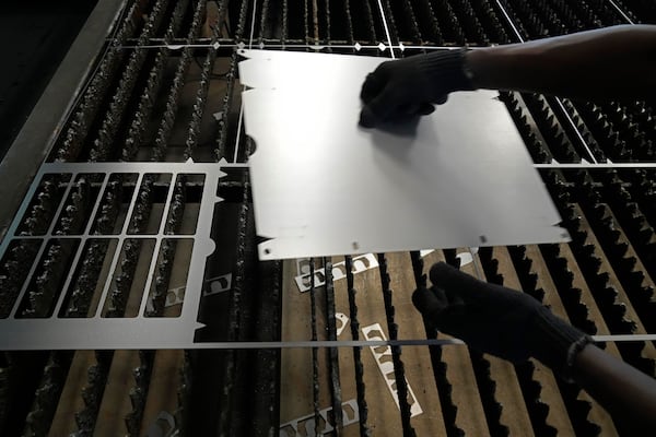 A worker lifts a steel sheet after cutting it in a specific design at a factory in a suburb of Bengaluru, India, Thursday, Feb. 27, 2025. (AP Photo/Aijaz Rahi)