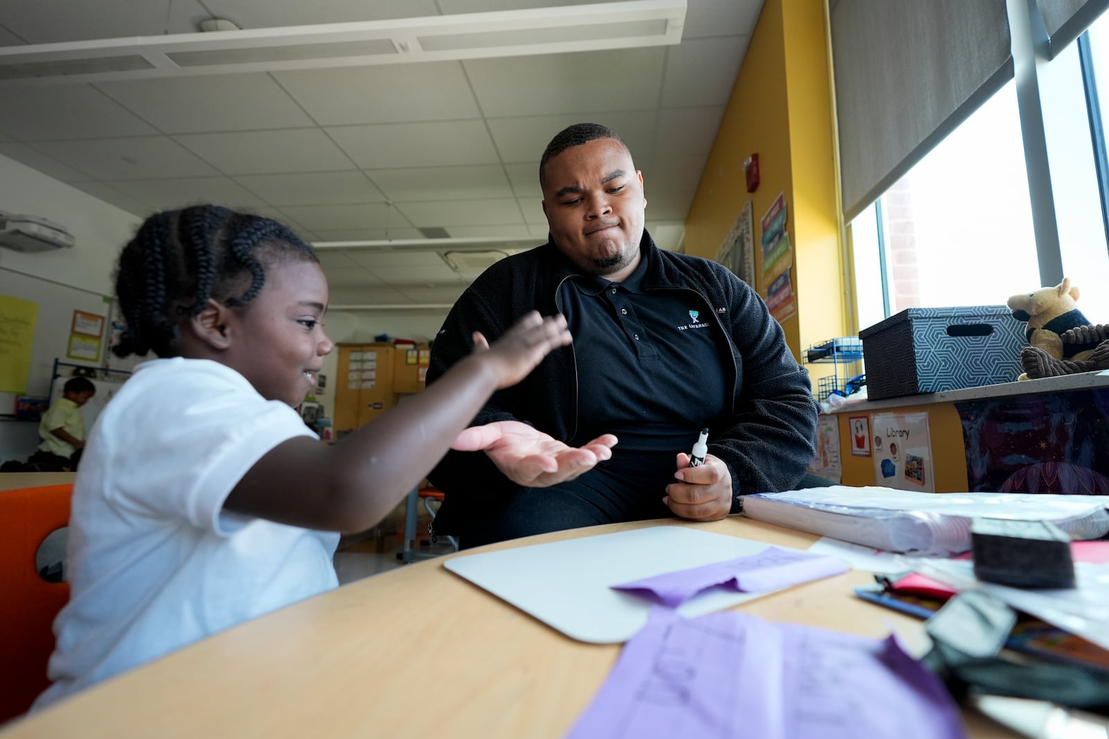 Leading Men fellow Davontez Johnson, right, high-fives preschooler Kodi during a name writing exercise, Thursday, Oct. 3, 2024, at Dorothy I. Height Elementary School in Baltimore. (AP Photo/Stephanie Scarbrough)