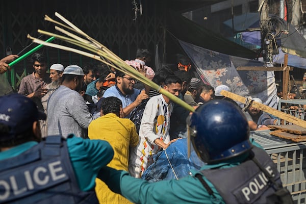 Policemen use batons to disperse the supporters of the banned Islamist group Hizbut Tahrir near Baitul Mokarram Mosque in Dhaka, Bangladesh, Friday, March 7, 2025. (AP Photo/Mahmud Hossain Opu)