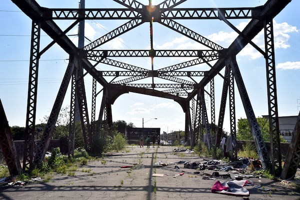 The so-called Bridge to Nowhere is located just north of Atlanta’s shiny new, billion-dollar Mercedes-Benz stadium. Closed in the early 1990s and partially demolished, it now serves as a shelter for a handful of homeless men and women. With a panoramic view of the city, what’s left of the bridge is now strewn with orange cones, plastic beads, tiki torches, piled up wrappers, and piles of garbage, tin foil with black burn markings, and syringes. A mattress. Leather couch. Blue tent. (Hyosub Shin / Hyosub.Shin@ajc.com)