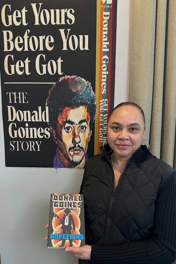 Donna Sailor poses next to poster of upcoming documentary about the life of her father and urban literature writer Donald Goines on Wednesday, March 12, 2025 in Detroit. (AP Photo/Corey Williams)