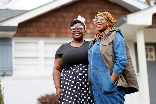 Erica Young (right) poses for a photograph with her wife, Daphne Williams, outside their new home in Atlanta on Tuesday. (miguel.martinezjimenez@ajc.com)