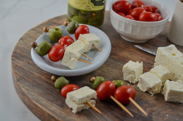 Olives, tomatoes and cubes of feta on toothpicks slow down the snacking. (Virginia Willis for The Atlanta Journal-Constitution)