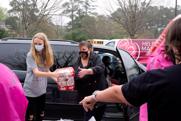 Helping Mamas workers hand off a pack of disposable diapers at a drive-up event in Marietta. Helping Mamas distributes free baby supplies to the metro Atlanta community through events hosted by their local partners. (Jamie Lackey/Helping Mamas)