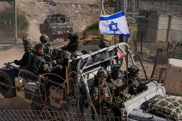 Israeli soldiers with the national flag stand on an armoured vehicle after crossing the security fence near the so-called Alpha Line that separates the Israeli-controlled Golan Heights from Syria, in the town of Majdal Shams, Thursday, Dec. 12, 2024. (AP Photo/Matias Delacroix)