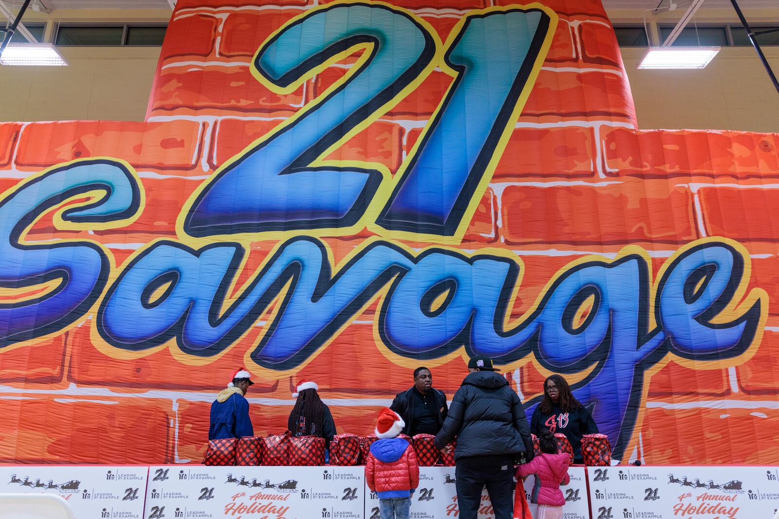 People receive gifts at the Wade Walker Park Family YMCA in Stone Mountain on Wednesday, December 21, 2022 . The event was put on by rapper 21 Savage’s Leading By Example foundation. (Arvin Temkar / arvin.temkar@ajc.com)