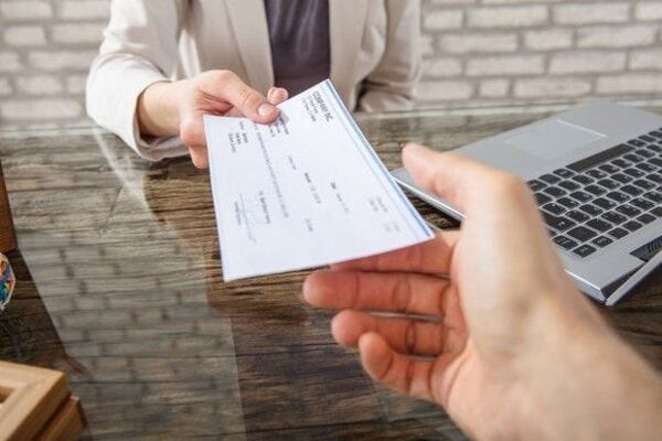 Woman handing check to man across desk