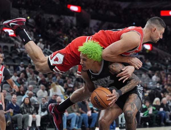 San Antonio Spurs forward Jeremy Sochan, bottom is fouled by Chicago Bulls center Nikola Vucevic, top, as he drives to the basket during the first half of an NBA basketball game in San Antonio, Thursday, Dec. 5, 2024. (AP Photo/Eric Gay)