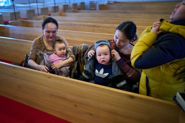 Worshippers put their coats on their soon after taking part in a religious service at a church in Nuuk, Greenland, Sunday, Feb. 16, 2025. (AP Photo/Emilio Morenatti)