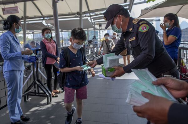 Health officials distribute protective face masks for visitors at a luxury mall in Bangkok, Thailand, Tuesday, Jan. 28, 2020. Panic and pollution drive the market for protective face masks, so business is booming in Asia, where fear of the new coronavirus from China is straining supplies and helping make mask-wearing the new normal. (AP Photo / Gemunu Amarasinghe)