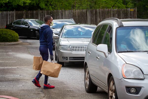 Members of the Pleasant Grove Baptist Church in Marietta carry bags of food out to cars during the church's food giveaway on Saturday, April 18. STEVE SCHAEFER / SPECIAL TO THE AJC