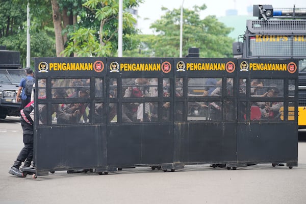 Police officers set up a barricade during a student protest against the passing of a new military law allowing active military personnel to hold more civilian posts, outside the parliament in Jakarta, Indonesia, Thursday, March 20, 2025. (AP Photo/Tatan Syuflana)