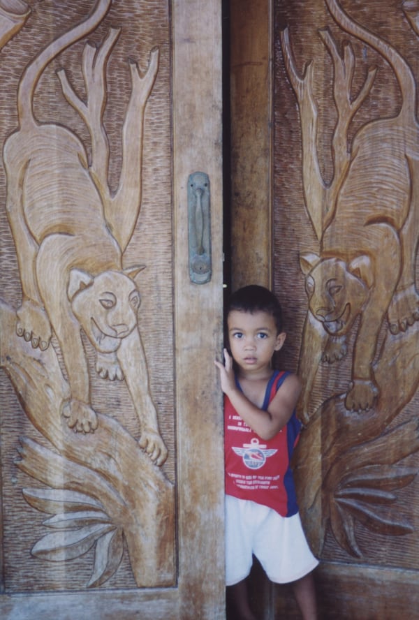 Axel Lopez Cruz, 3, looks out from the front doors of his family's home in Barra del Parismina, Costa Rica. The family is among locals who host homestays for visitors volunteering with the village-run turtle conservation project. The wooden doors with carvings of jaguars -- which inhabit jungles not far from Parismina -- came from the capital city of San Jose, Costa Rica.  (Brian J. Cantwell/Seattle Times/TNS)