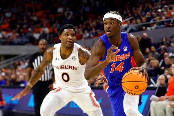 Florida guard Kowacie Reeves (14) drives to the basket around Auburn guard K.D. Johnson (0) during the first half of an NCAA basketball game Wednesday, Dec. 28, 2022, in Auburn, Ala. (AP Photo/Butch Dill)