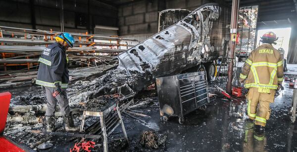 DeKalb County Fire Rescue investigator Henry Patterson (left) examines the truck that caught fire. 