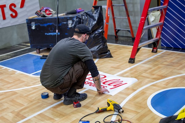 A worker rebrands a demonstration basketball court, sometimes used by analysts on broadcasts, at Fox Sports South's studios to reflect the new Bally Sports name.