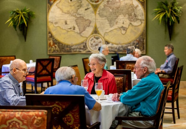 Residents at Canterbury Court including Clyde May, from left, Fritz Tourssaint, back to camera, Barbara Cheshire and Clyde Herron finish up their lunch in the dining room at Canterbury Court. During the worst of the pandemic, meals were delivered to their apartments and visitors were not allowed.  (Jenni Girtman for The Atlanta Journal Constitution)