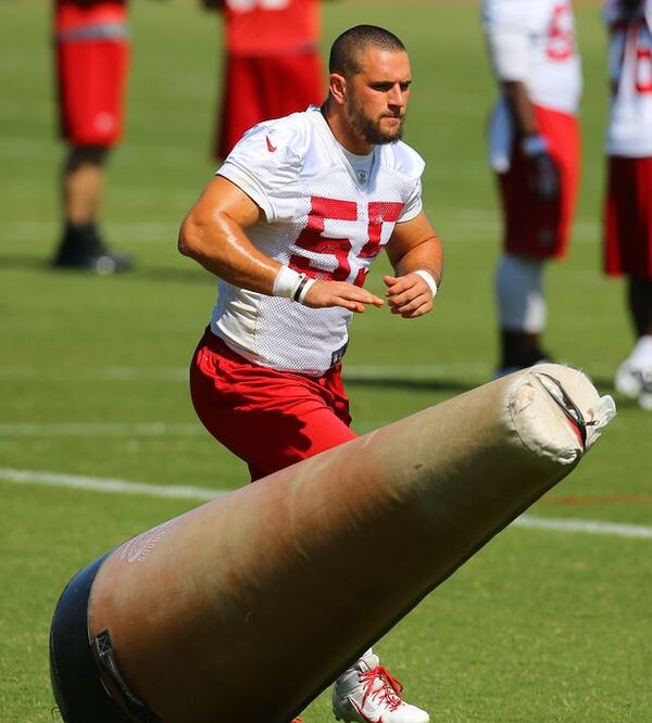 Falcons linebacker Paul Worrilow knocks over a tackling dummy running a drill during team practice on Tuesday, June 10, 2014, in Flowery Branch. (By Curtis Compton/Ccompton@ajc.com)