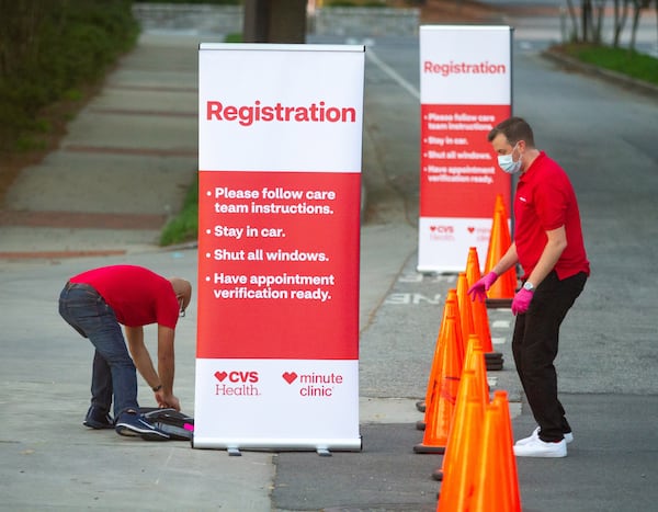 CVS employees Roland Archibald, left, and Dan Badstubner set up signage in preparation for the opening of a COVID-19 drive-thru testing center in Atlanta.