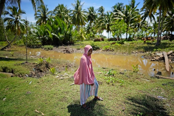 Munirpa, a crocodile attack survivor, stands for a portrait at the location where she was nearly killed by a four-meter-long crocodile, in Topoyo, West Sulawesi, Indonesia, Monday, Feb. 24, 2025. (AP Photo/Dita Alangkara)