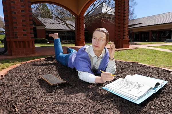 The life-size, realistic sculpture titled, “Summer Thinking,” by Seward Johnson is shown, Thursday, March, 20, 2025, in Monroe, Ga. There are 10 statues that can be seen playing chess on a side street, playing music on the corner of the town green, hailing a cab holding an umbrella or a police officer writing a ticket in front of a parking space, among others. The sculptures will be in downtown Monroe until February 2026. (Jason Getz / AJC)