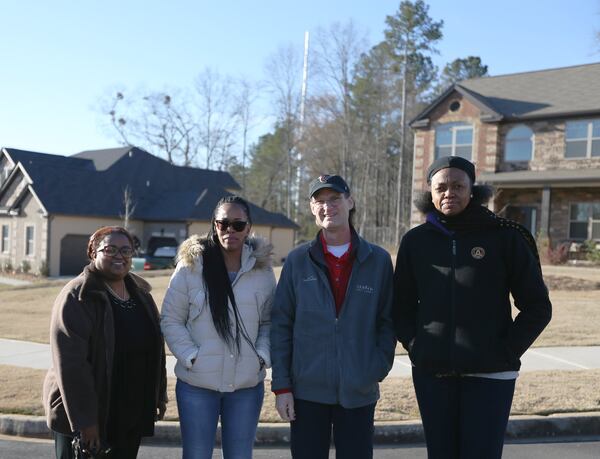 From left: Katrina Langford, Lynn Goodwin, Phillip Kelly and Virginia Pierce-Kelly pose for a portrait with the cell tower that was put up right by their neighborhood in Stonecrest. (Photo: EMILY HANEY / emily.haney@ajc.com)