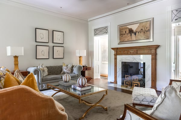 Flanking the other side of the home, the sun room features a warm clash of white cream and natural wood colors. The nearby marbled-floor bathroom takes you back to the 1920s for a vintage experience. In the bedroom, a trio of draped windows allow you to be greeted by the natural lighting of your gardens each morning.