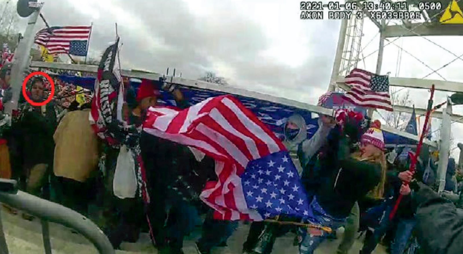 This image from a police-worn body camera and provided and annotated by the Justice Department shows Jeffrey Newcomb, 41, of Polk, Ohio, circled in red, on the East Front of the U.S. Capitol, Jan. 6, 2021, in Washington. Newcomb was arrested Oct. 22, 2024, on charges that he brought a massive "Trump" sign to the U.S. Capitol and joined other rioters in using it as a weapon against police officers during a mob attack. (Department of Justice via AP)