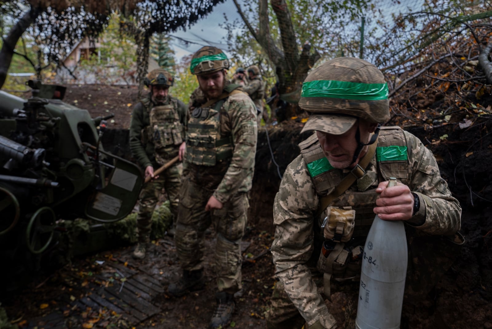 Ukrainian serviceman of Khartia brigade carries shell to the D-30 Howitzer in order to fire towards Russian positions in Kharkiv region, Ukraine, Wednesday, Oct. 16, 2024. (AP Photo/Alex Babenko)