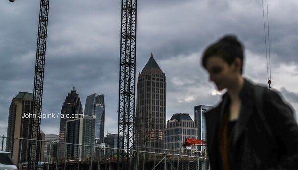 Sidney Haltom makes her way to work along 17th and Market streets under a layer of gray clouds Tuesday morning. Those clouds will produce heavier showers and downpours in the afternoon, according to the latest forecast.