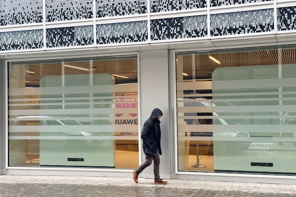 A man walks by the headquarters of Huawei in Brussels, Thursday, March 13, 2025. (AP Photo/Sylvain Plazy)