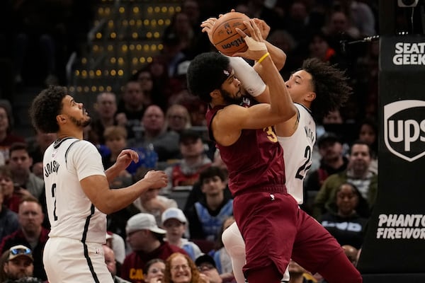 Brooklyn Nets forward Jalen Wilson, right, fouls Cleveland Cavaliers center Jarrett Allen, center, as forward Cameron Johnson (2) looks on in the second half of an NBA basketball game, Tuesday, March 11, 2025, in Cleveland. (AP Photo/Sue Ogrocki)