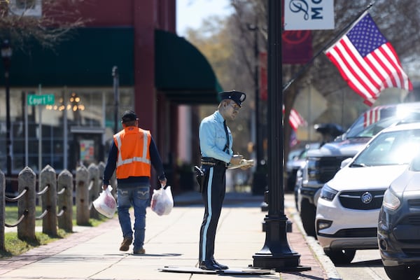 The life-size, realistic sculpture titled, “Time’s Up,” by Seward Johnson is shown, Thursday, March, 20, 2025, in Monroe, Ga. There are 10 statues that can be seen playing chess on a side street, playing music on the corner of the town green, hailing a cab holding an umbrella or a police officer writing a ticket in front of a parking space, among others. The sculptures will be in downtown Monroe until February 2026. (Jason Getz / AJC)