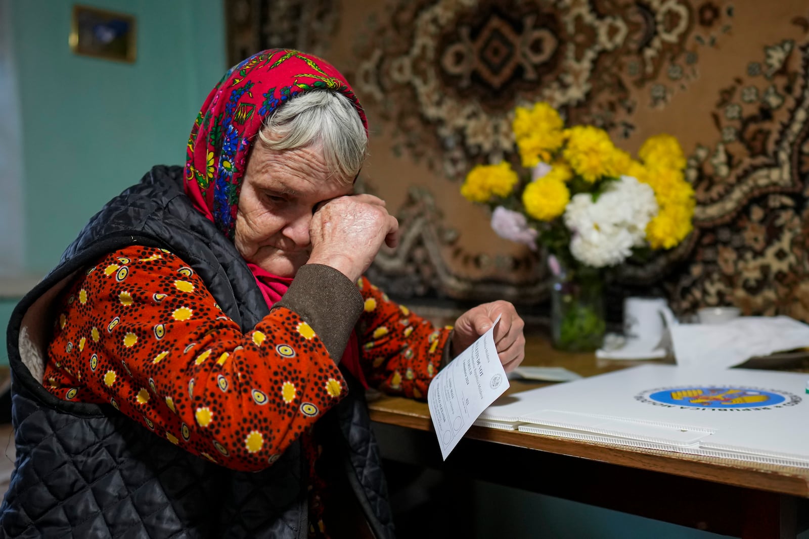 A woman wipes her eyes before casting her vote in a mobile ballot box during a presidential election runoff, in the village of Ciopleni, Moldova, Sunday, Nov. 3, 2024. (AP Photo/Vadim Ghirda)