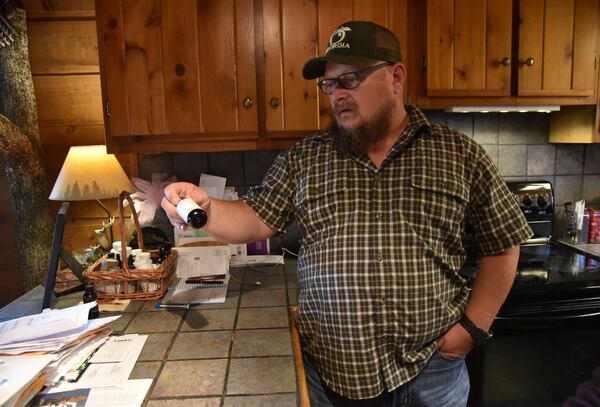 Jim “J-Bo” Wages holds a bottle of cannabis oil for his daughter Sydney at their home in Dallas on Feb. 8, 2017. The family was among the very first to receive permission from Georgia to use low-dose cannabis oil without fear of prosecution. HYOSUB SHIN / HSHIN@AJC.COM