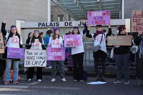 Activists hold posters in front of the Palace of Justice during a women's rights demonstration, Saturday, Dec. 14, 2024 in Avignon, southern France, where the trial of dozens of men accused of raping Gisèle Pelicot while she was drugged and rendered unconscious by her husband is taking place. (AP Photo/Aurelien Morissard)