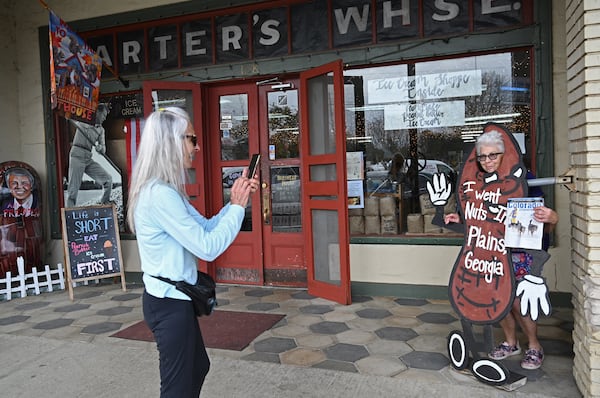 Donna Peardon (left), of Spring Hill, Florida, takes a picture of her friend Cathy Carroll of Calhan, Colorado, as she holds a Colorado magazine in front of Bobby Salter's Plain Peanuts and General Store, Thursday, Feb. 23, 2023, in Plains, GA. Donna Peardon and Cathy Carroll decided come to Plains after they heard President Jimmy Carter entered home hospice care. (Hyosub Shin / Hyosub.Shin@ajc.com)