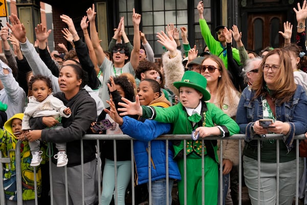 Graham Johnston, of St. Louis, Mo., dressed as a leprechaun, and others reach for treats thrown by participants at the St. Patrick's Day parade, Sunday, March 16, 2025, in Boston, Mass. (AP Photo/Robert F. Bukaty)