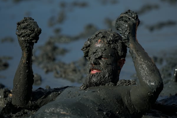 A reveler rolls in the mud during the traditional Mud Block carnival party in Paraty, Brazil, Saturday, March 1, 2025. (AP Photo/Andre Penner)