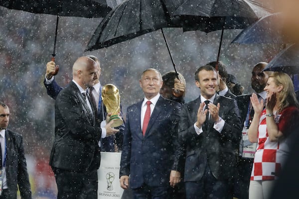 FILE - From left to right, FIFA President Gianni Infantino, Russia's President Vladimir Putin, France's President Emmanuel Macron and Croatia's President Kolinda Grabar-Kitarovic stand under the pouring rain during the awards ceremony after final match between France and Croatia at the 2018 soccer World Cup in the Luzhniki Stadium in Moscow, Russia, Sunday, July 15, 2018. (AP Photo/Natacha Pisarenko, File)