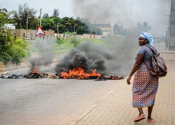 A woman walks past a barricade set fire by protesters in Maputo, Mozambique, Thursday, Nov. 7, 2024. Protesters dispute the outcome of the Oct. 9 elections that saw the ruling Frelimo party extend its 49-year rule. (AP Photo/Carlos Uqueio)