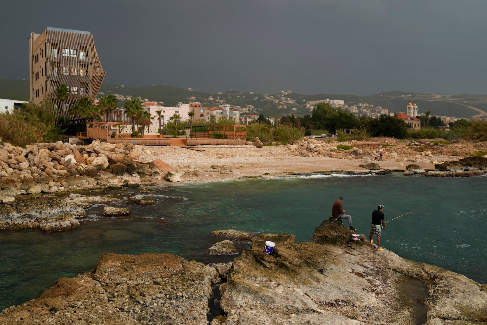 Lebanese fishermen cast their fishing rods at a beach in Batroun, northern Lebanon, Saturday, Nov. 2, 2024, where Lebanese officials say a ship captain was taken away by a group of armed men who landed on a coast north of Beirut and they're investigating whether Israel was involved. (AP Photo/Hussein Malla)