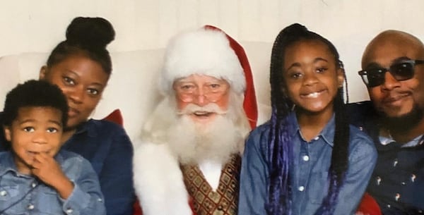 Ayesha Shearn of Alpharetta and her husband, Les, have been getting by by going into debt, so they are anxious to get federal help. Here she and her husband along with their children pose with a family friend.  