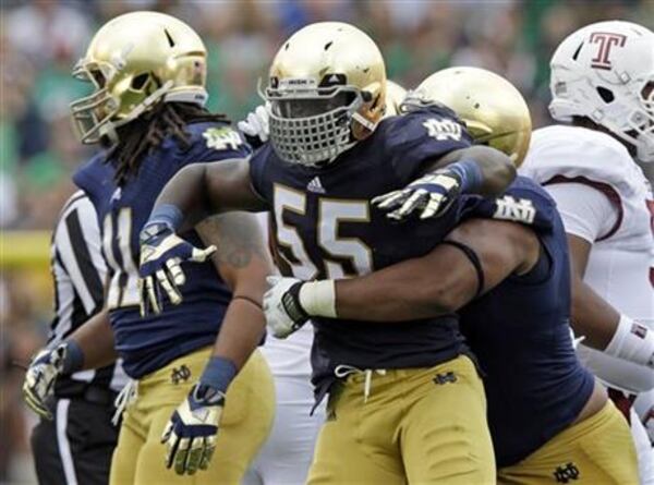 Notre Dame linebacker Prince Shembo (55) celebrates as he's hugged by teammate Stephon Tuitt after a tackle for a loss against Temple during the first half of an NCAA college football game in South Bend, Ind., Saturday, Aug. 31, 2013. (AP Photo/Michael Conroy)