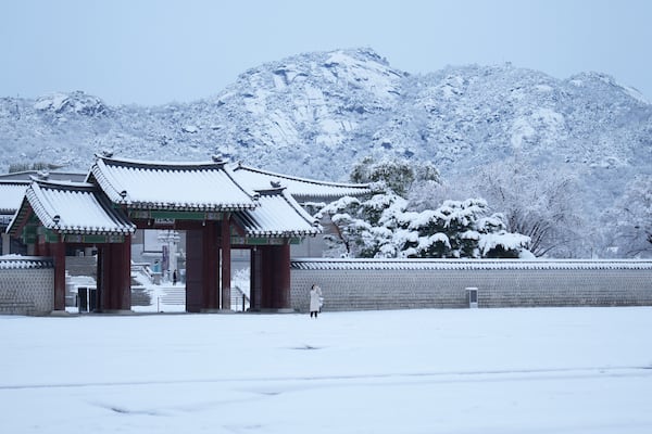 A visitor holds her smartphone outside of the snow-covered National Palace Museum in Seoul, South Korea, Wednesday, Nov. 27, 2024. (AP Photo/Lee Jin-man)