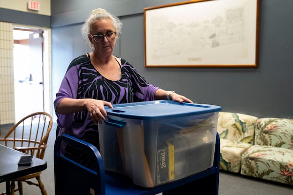 Pam Walton packs her container with the photographs and lists of "Two by Twos" conventions, members and ministers, at a library Monday, Dec. 9, 2024, in Wailea, Hawaii. (AP Photo/Mengshin Lin)