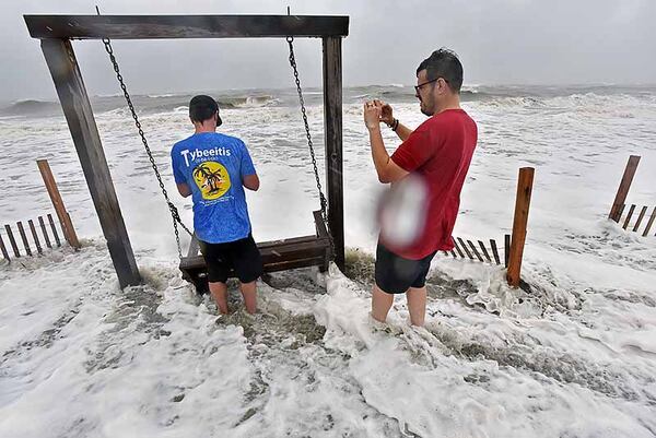 Brett Lay (left) and James Simpson take pictures in the waters off Tybee Island.