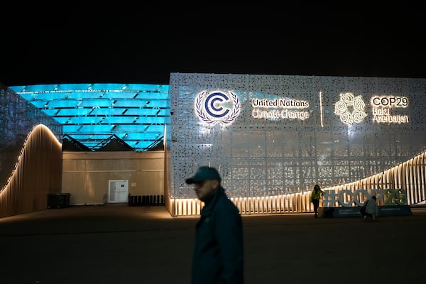 People walk outside the venue for the COP29 U.N. Climate Summit, Monday, Nov. 11, 2024, in Baku, Azerbaijan. (AP Photo/Rafiq Maqbool)