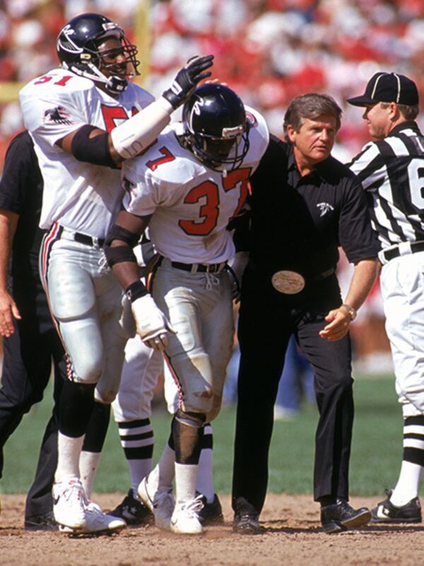 Cornerback Elbert Shelley is help off the field by head coach Jerry Glanville after a hit during a game against the San Francisco 49ers at Candlestick Park in 1990. (George Rose/Getty Images)