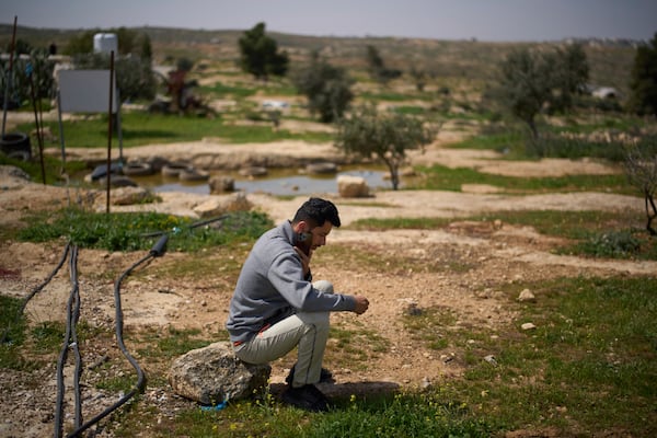 Basel Adra, one of the directors of the Oscar winner documentary "No Other Land", speaks on the phone as he sits in an area near the house of Palestinian co-director Hamdan Ballal, in the village of Susiya in Masafer Yatta, south Hebron hills Tuesday, March 25, 2025. (AP Photo/Leo Correa)